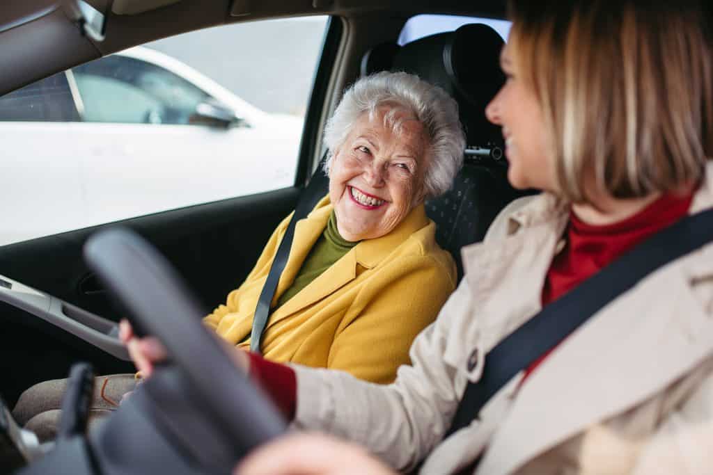 Senior woman smiling during in-home support service with caregiver.