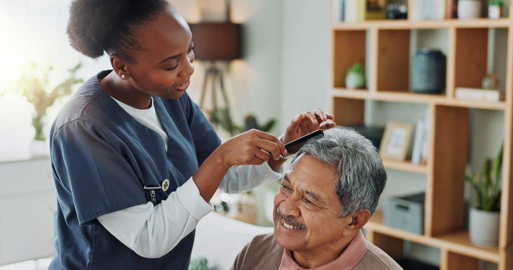 Caregiver assisting elderly man with personal grooming at home.