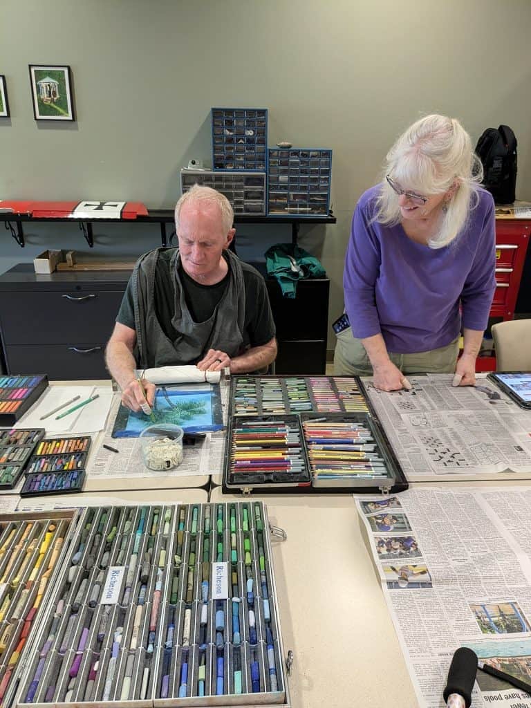 Two seniors working on art projects at a creative workshop.