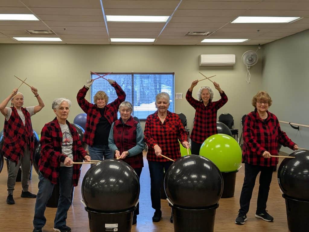 Senior women engaging in drumming activity at Four Pointes Center for Successful Aging.