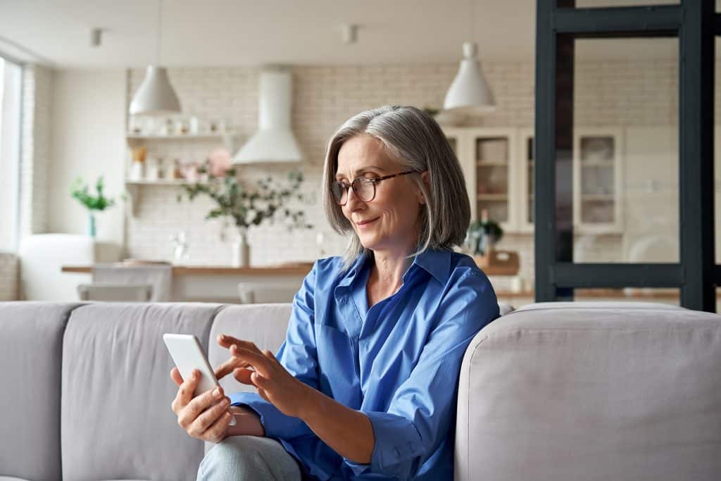 Senior woman using smartphone in modern living room for communication.