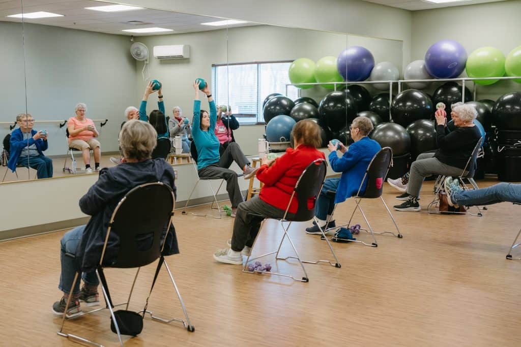 Older adults participating in seated and standing exercise activities at Four Pointes Center.