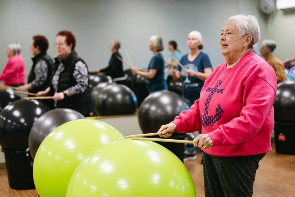 Elderly women participating in fitness class with stability balls in gym.