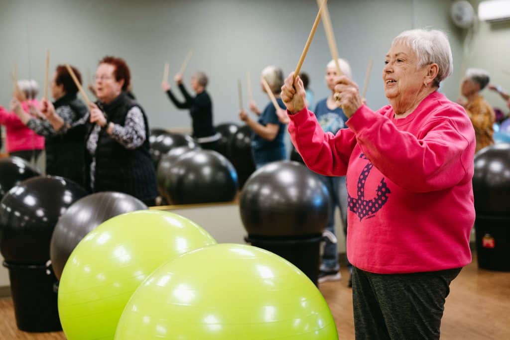 Elderly women participating in a senior exercise class with stability balls and drumsticks.