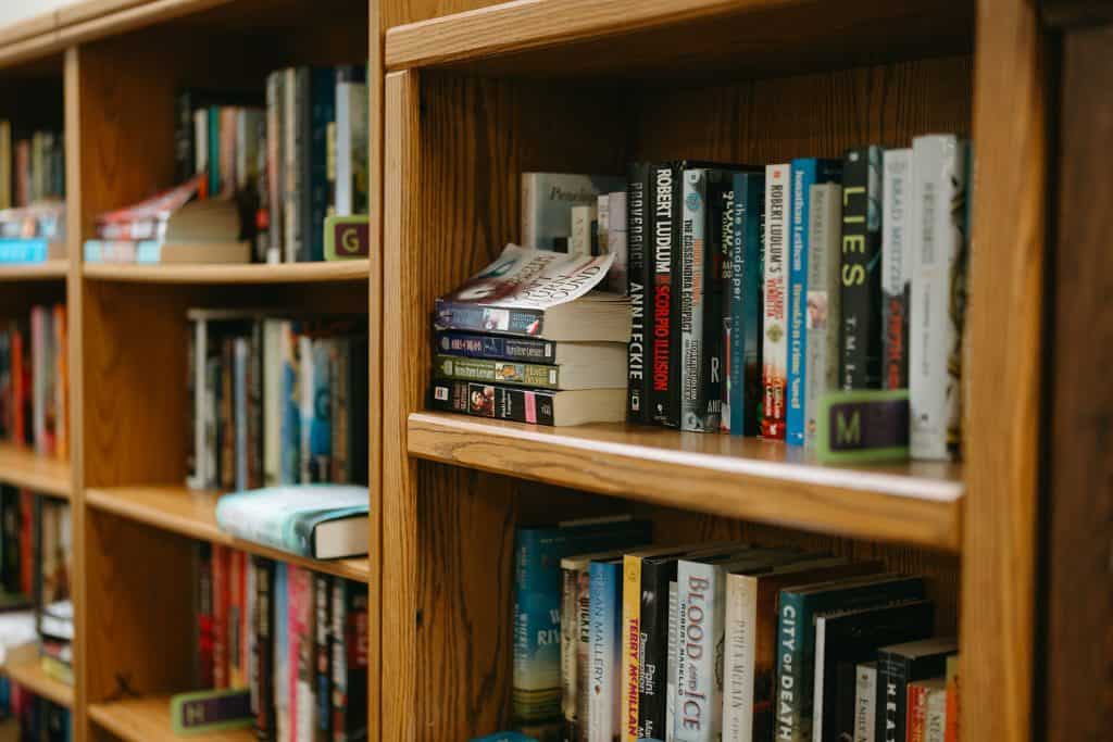 Wooden bookshelf filled with various books in a library or bookstore setting.