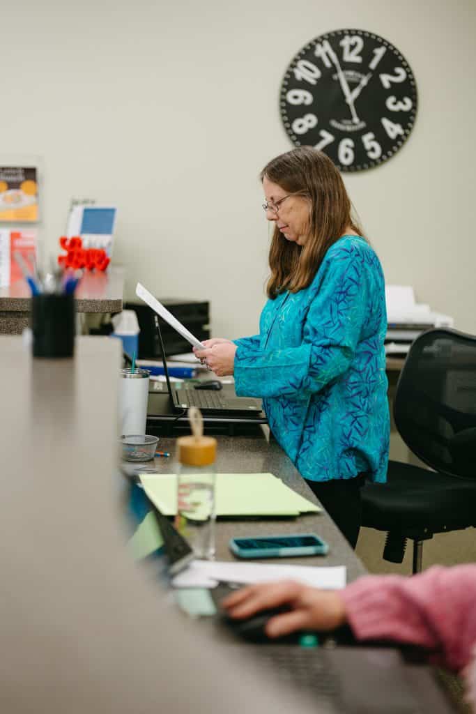 Woman reviewing documents at her desk in an office setting.