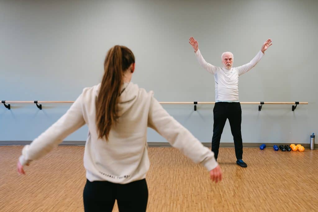 Senior woman exercising with instructor in fitness class at All Season Innovations.