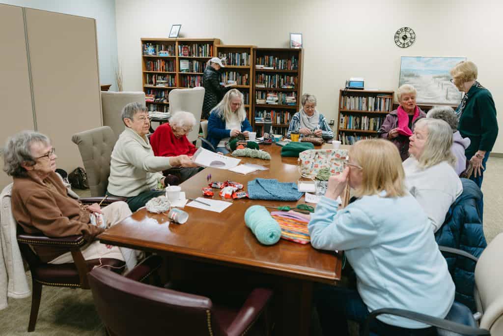 Group of elderly women engaging in crafting activities at a library.