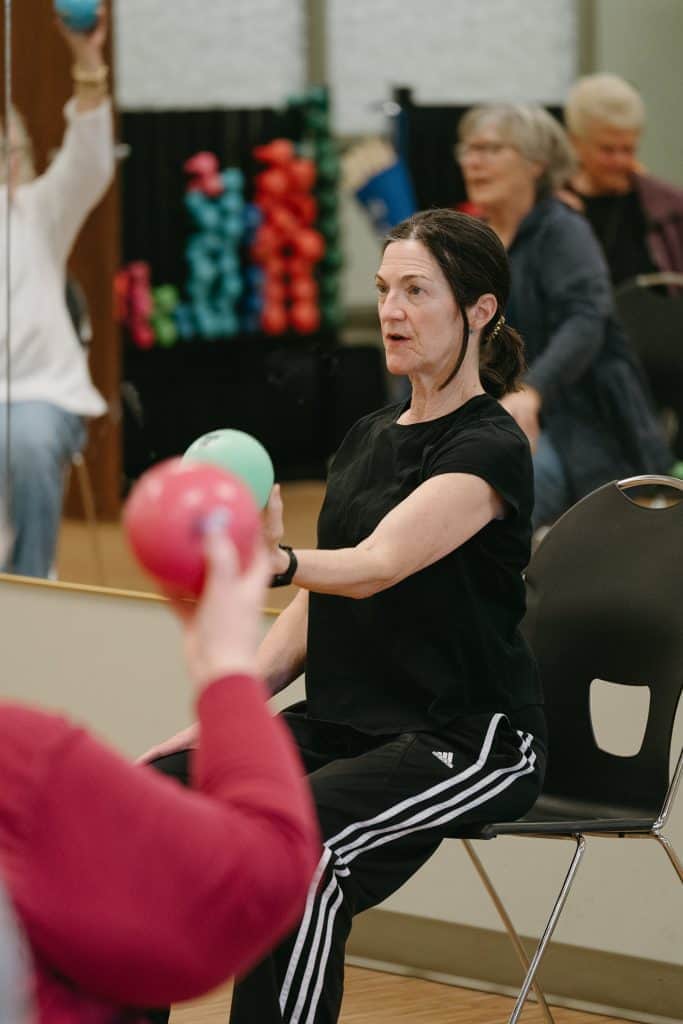 Older woman participating in a seated exercise class at Four Pointes Center.