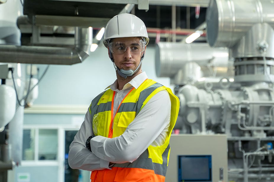 Ingegnere o tecnico in DPI (casco e giubbotto) in un impianto industriale, simbolo di etica, sicurezza e professionalità Nepta.