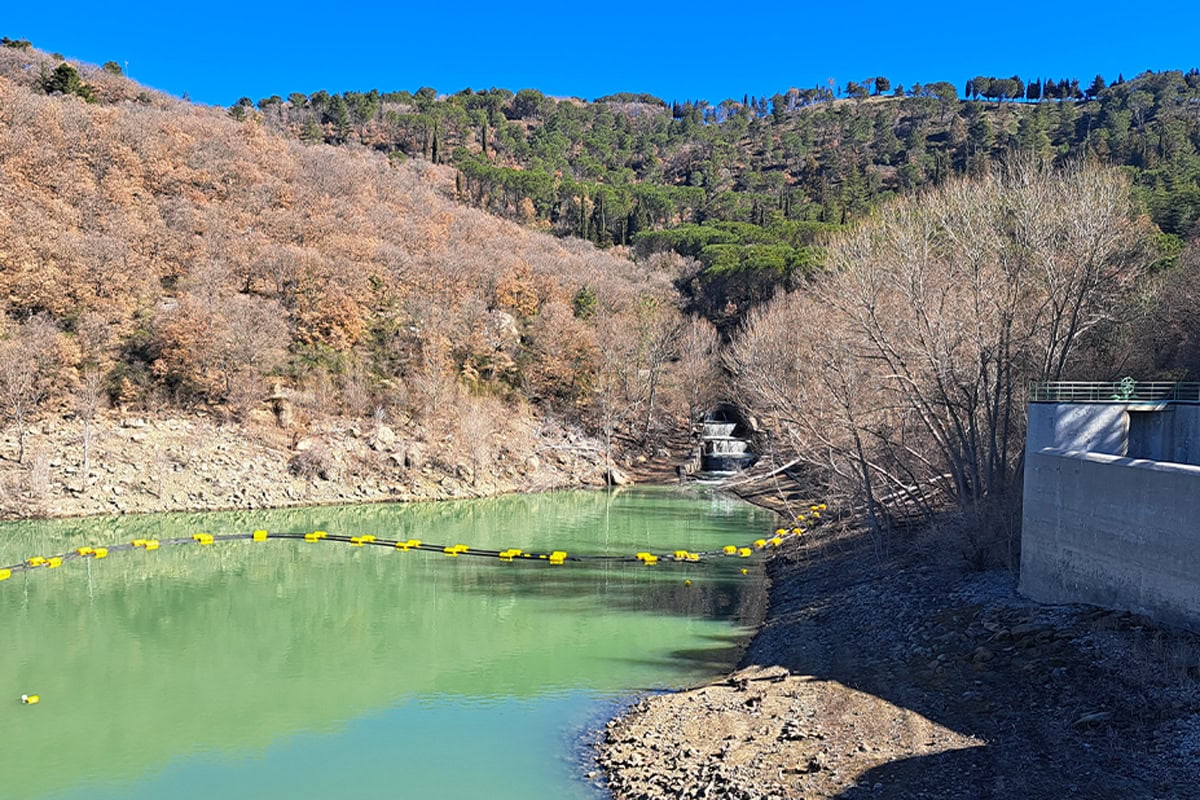 Vista di un bacino idrico o di una diga in una zona collinare con l'imbocco di un tunnel di derivazione visibile al centro. L'immagine rappresenta il punto di inizio della nuova condotta del raddoppio dell'Acquedotto Garcia di Siciliacque/Nepta, che aumenterà la portata complessiva da 530 a 730 litri al secondo.