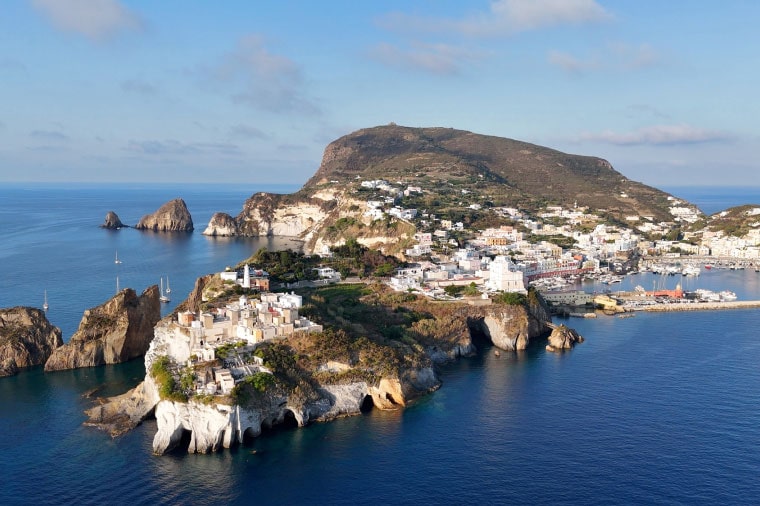 Veduta aerea di Ponza con scogliera, spiaggia e porto turistico affollato. L'immagine simboleggia le località costiere e insulari gestite da Acqualatina S.p.A.
