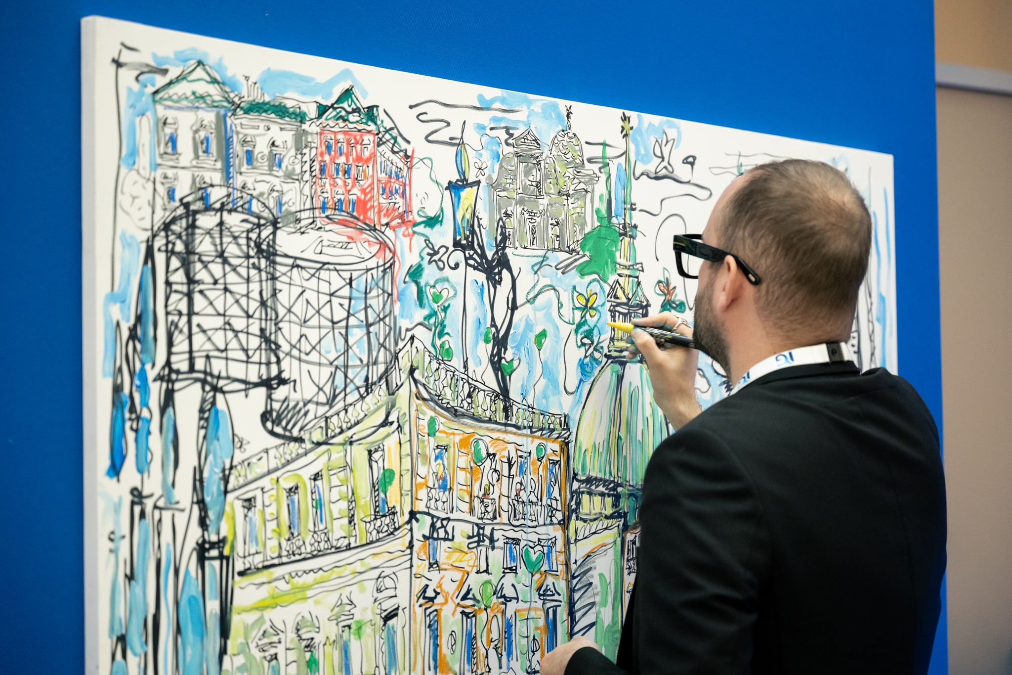 Man drawing on canvas with urban and nature sketches for Italgas Planet Week event.