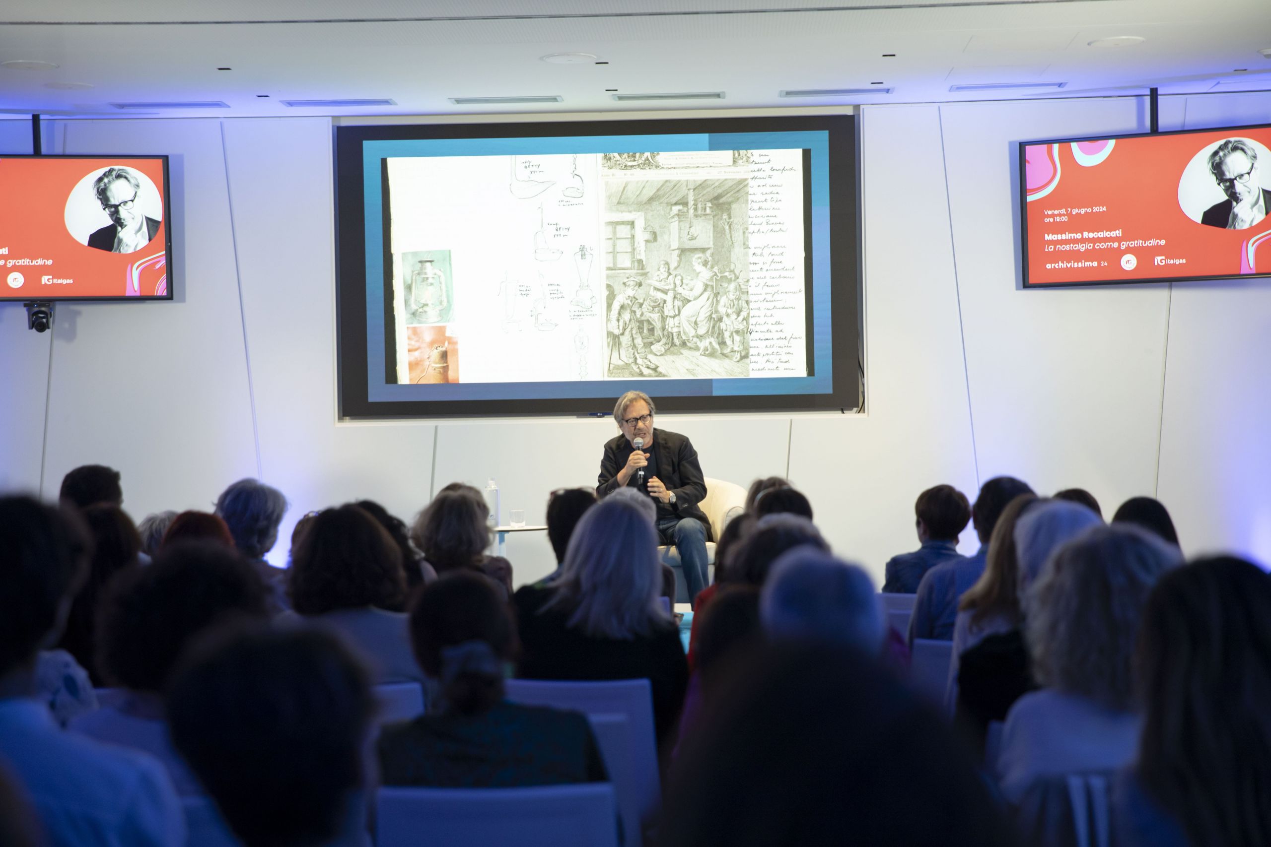 Event speaker at Heritage Lab, with audience and presentation slides in the background.
