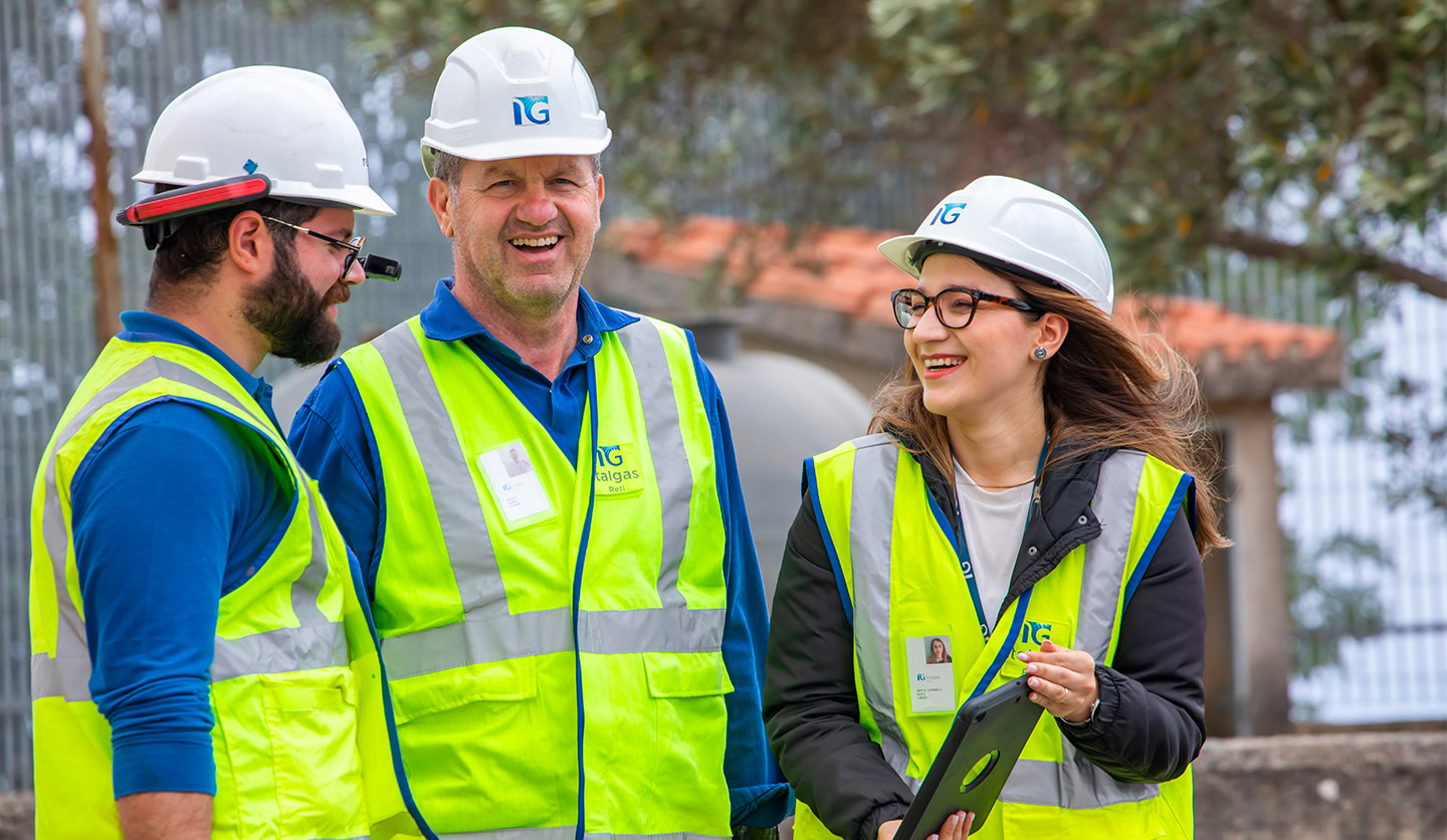 Italgas employees in reflective jackets smile while working, symbolizing training and professional growth.