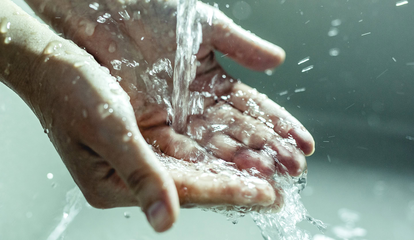 Hands collecting clear water symbolize the water service managed by Italgas in 2023.
