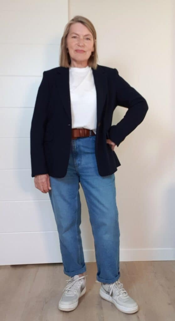 Woman over 60 wearing a navy blazer over a simple white tee and jeans