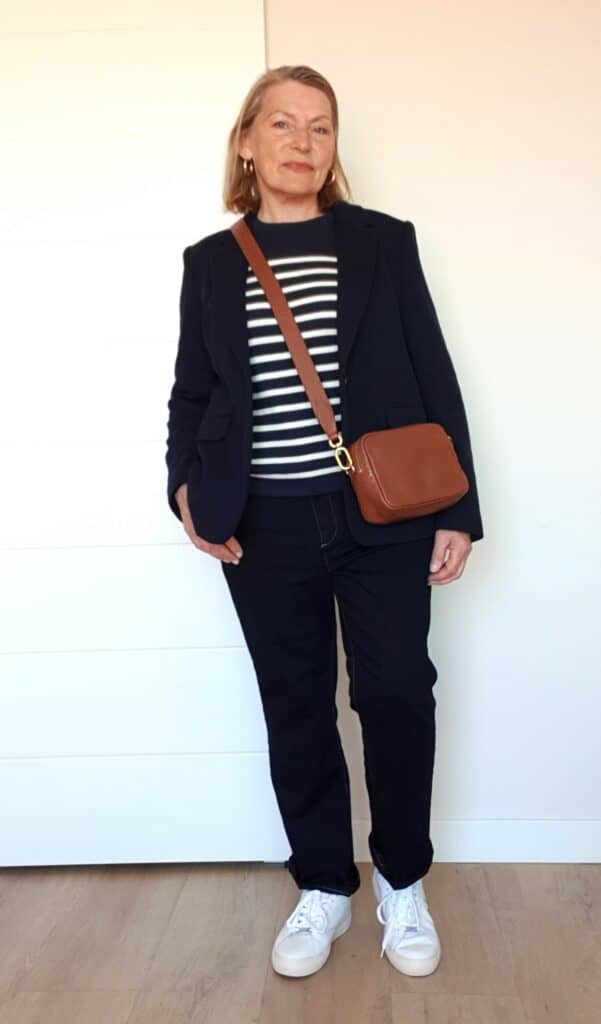 Woman over 60 wearing a navy blazer with a striped top and white sneakers