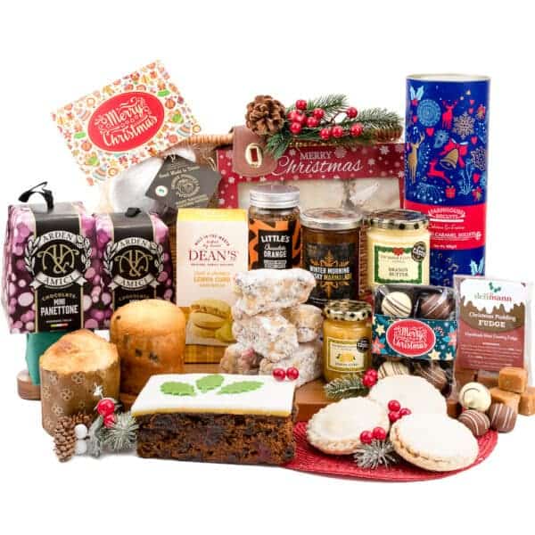 A large festive hamper on a white background full of festive goodies, mince pies, mini panettone, chocolate truffles, salted caramel cookies, brandy butter, lemon biscuits, iced christmas fruit cake and lots more.