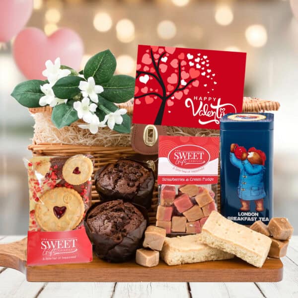 The 'With Love' Paddington Bear Gift Hamper is a Valentine's hamper filled with muffins, shortbread, fudge, a tea tin, and a card, themed around Paddington's Afternoon Tea Break.