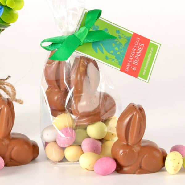 Solid Chocolate Easter Bunnies & Mini Eggs wrapped in plastic feature vibrant Mini Eggs at the base, elegantly adorned with a green ribbon and tag.