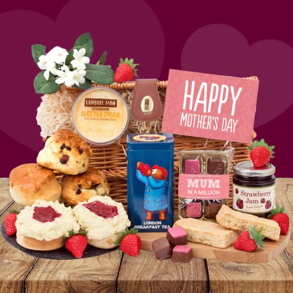 The Mum’s Paddington Cream Tea Gift Hamper, featuring scones, clotted cream, strawberry jam, chocolates, tea, biscuits, a "Happy Mother’s Day" card and flowers, sits on wood with a heart-patterned purple background.