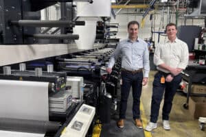 Chris Dillon and Michael Dillon, alongside one of the three presses that have been upgraded to run UV LED curing.