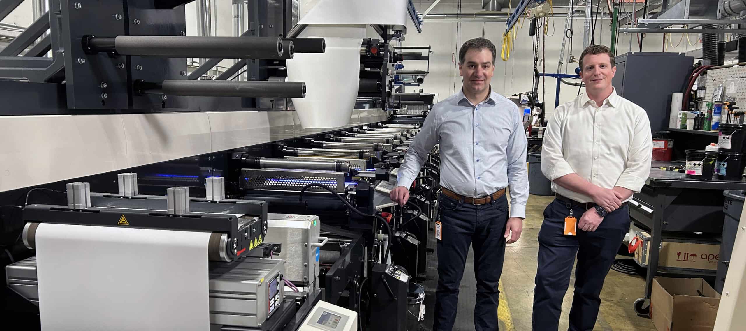 Chris Dillon and Michael Dillon, alongside one of the three presses that have been upgraded to run UV LED curing.