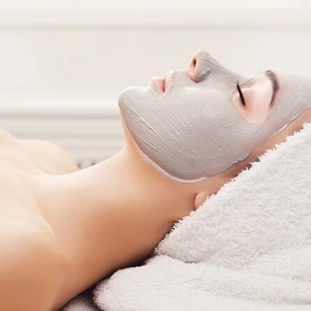 Face mask, spa beauty treatment, skincare Face mask, spa beauty treatment. Woman applying facial clay mask at spa salon, skincare, side vies