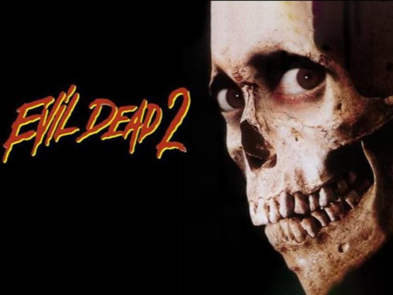 Poster for “Evil Dead 2” showing a skull with human-like eyes on a dark background—perfect for fans of horror films—title in stylized yellow and red text to the left.