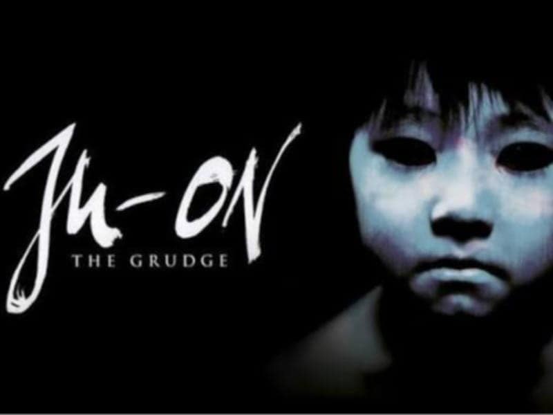 Poster for “Ju-On: The Grudge” featuring white text on black and a close-up of a child’s face with pale skin and dark, hollow eyes—a must-see for 31 Days of Horror Movies.