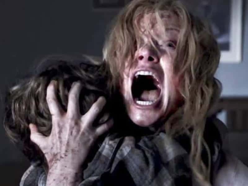A distressed woman with disheveled hair screams while holding a child tightly—a chilling scene perfect for 31 Days of Horror Movies.