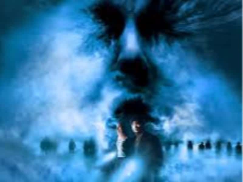 A man and woman stand in a blue mist with shadowy figures behind them and a large, ghostly face looming, evoking classic Horror Movies.