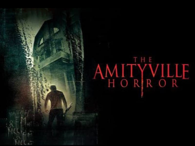 A man holding an axe stands before a dark, ominous house; “The Amityville Horror” is written in red—perfect for your 31 Days of Horror Movies.