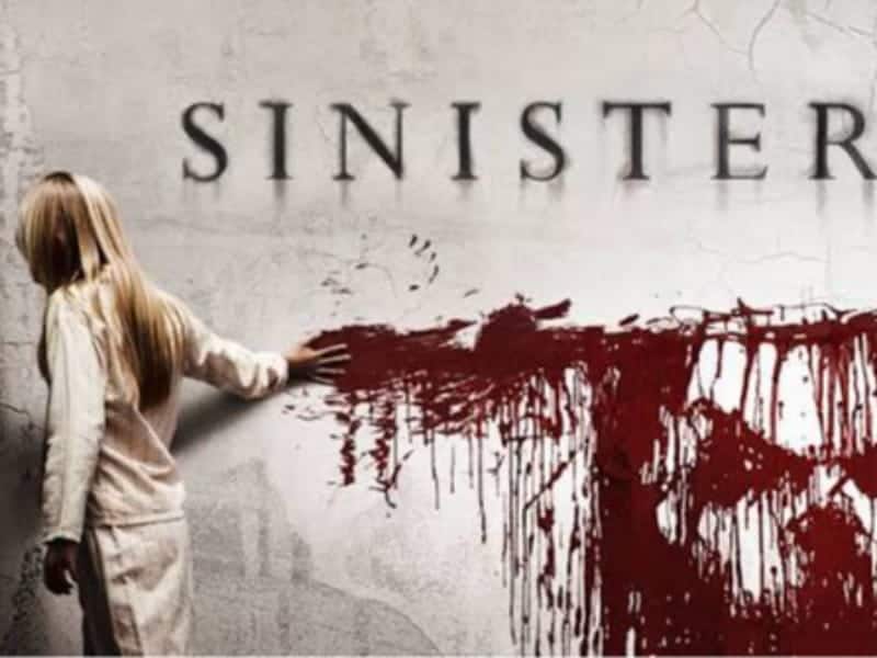 A person in light clothing touches a blood-stained wall beneath the word “SINISTER” in large black letters, evoking classic 31 days of horror movies.