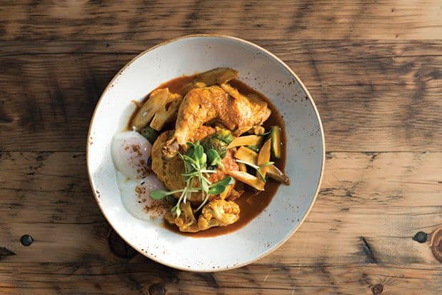 A plate of curry on a wooden table.