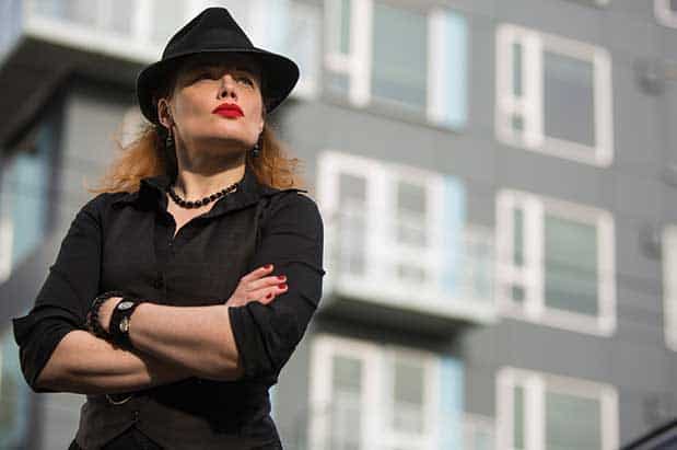 A woman in a black hat standing in front of a building.