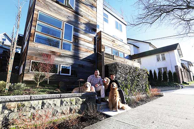 A family sits on the steps of a house with a dog.