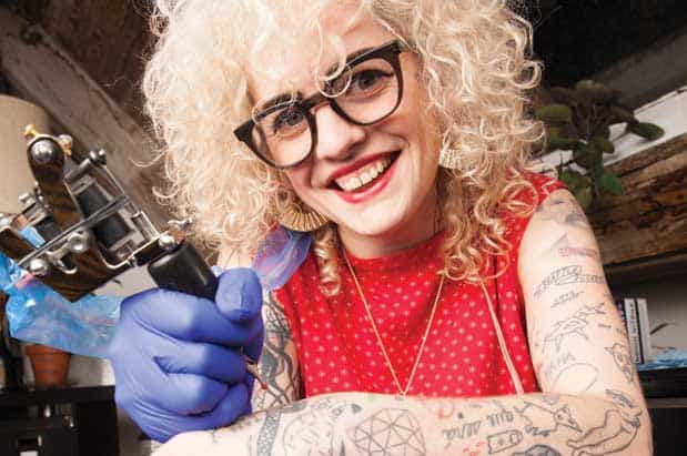 A woman with a tattoo on her arm holding a tattoo machine.