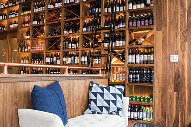 A bar with wine bottles on the wall.