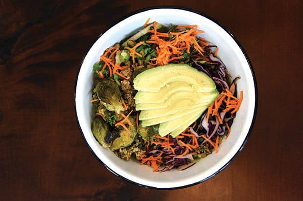 A bowl of a salad with carrots, brussels sprouts and avocado.