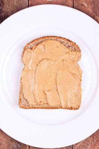 A slice of bread with peanut butter on it.