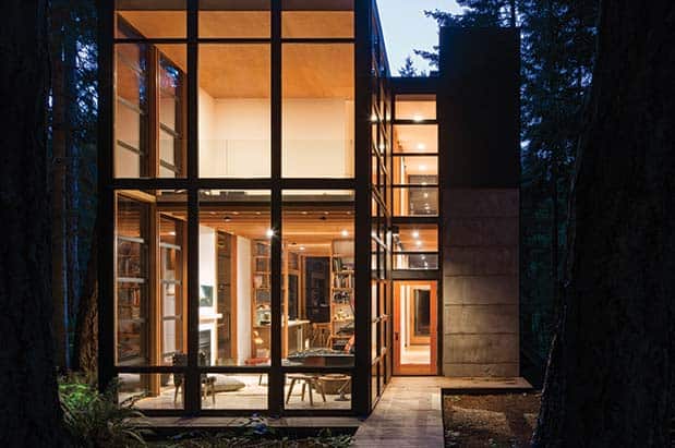 A modern house in the woods at night.