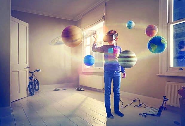 A boy wears a virtual reality headset gazing in wonder into a virtual solar system that has taken over his bedroom.