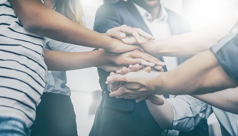 Close up view of young business people putting their hands together. Stack of hands. Unity and teamwork concept.