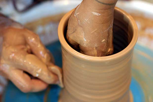 A person is making a pot on a pottery wheel.