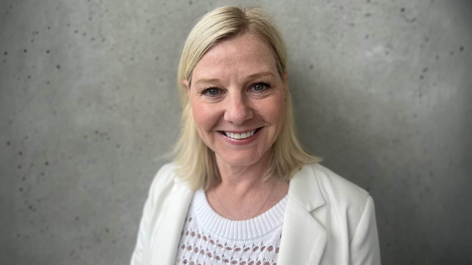 Jane-Broom-Davidson_1600x900 Woman with blonde hair and a white outfit smiling in front of a grey textured wall, Jane Broom Davidson, who just landed the coolest job ever at Microsoft.