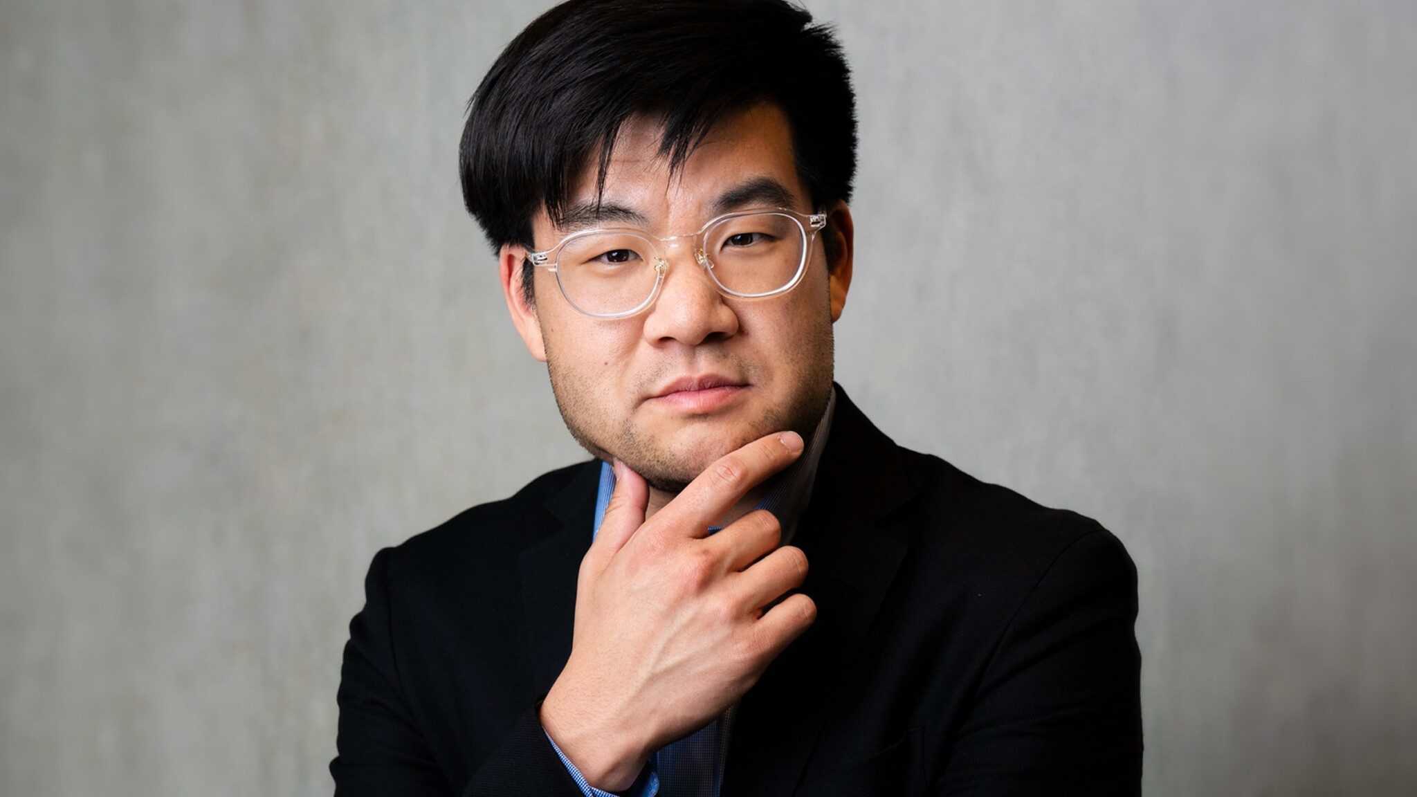 Sam-Cho-1_16x9-min A man in glasses and a black suit appears contemplative with his hand on his chin, uncommonly evoking the essence of thinkers.