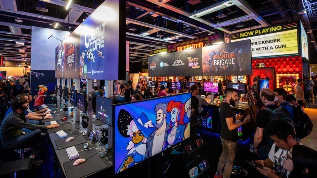 Attendees at a busy gaming convention in Seattle interact with various game demos and displays. Many booths showcase different games, with colorful posters of Pikachu and Mario on monitors, and people are engaged in playing and watching.