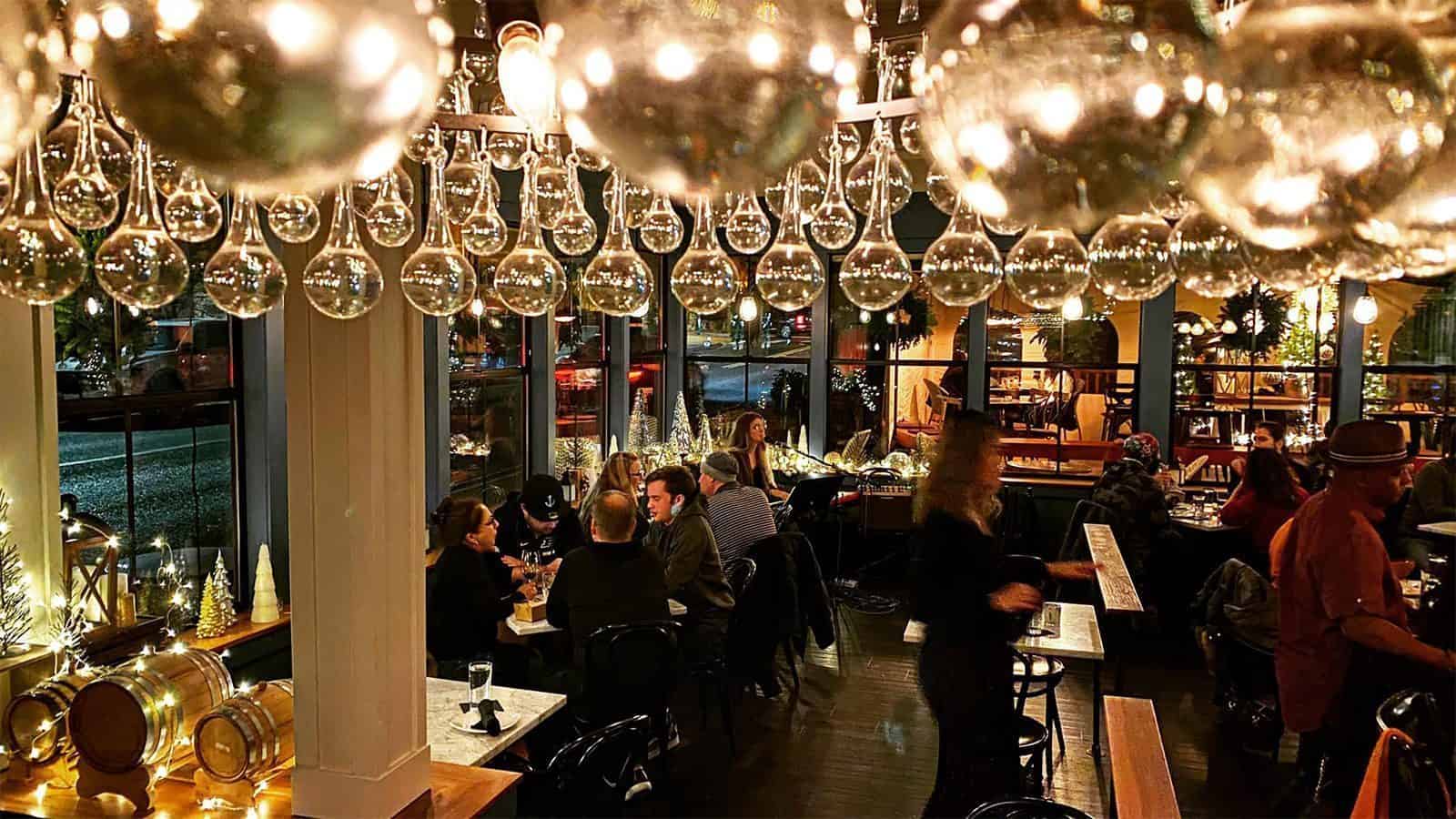 A warmly lit, bustling restaurant in Bothell with patrons dining and engaging in conversation. Decorative hanging lights and festive decor enhance the cozy atmosphere, making it a hidden gem in Washington.